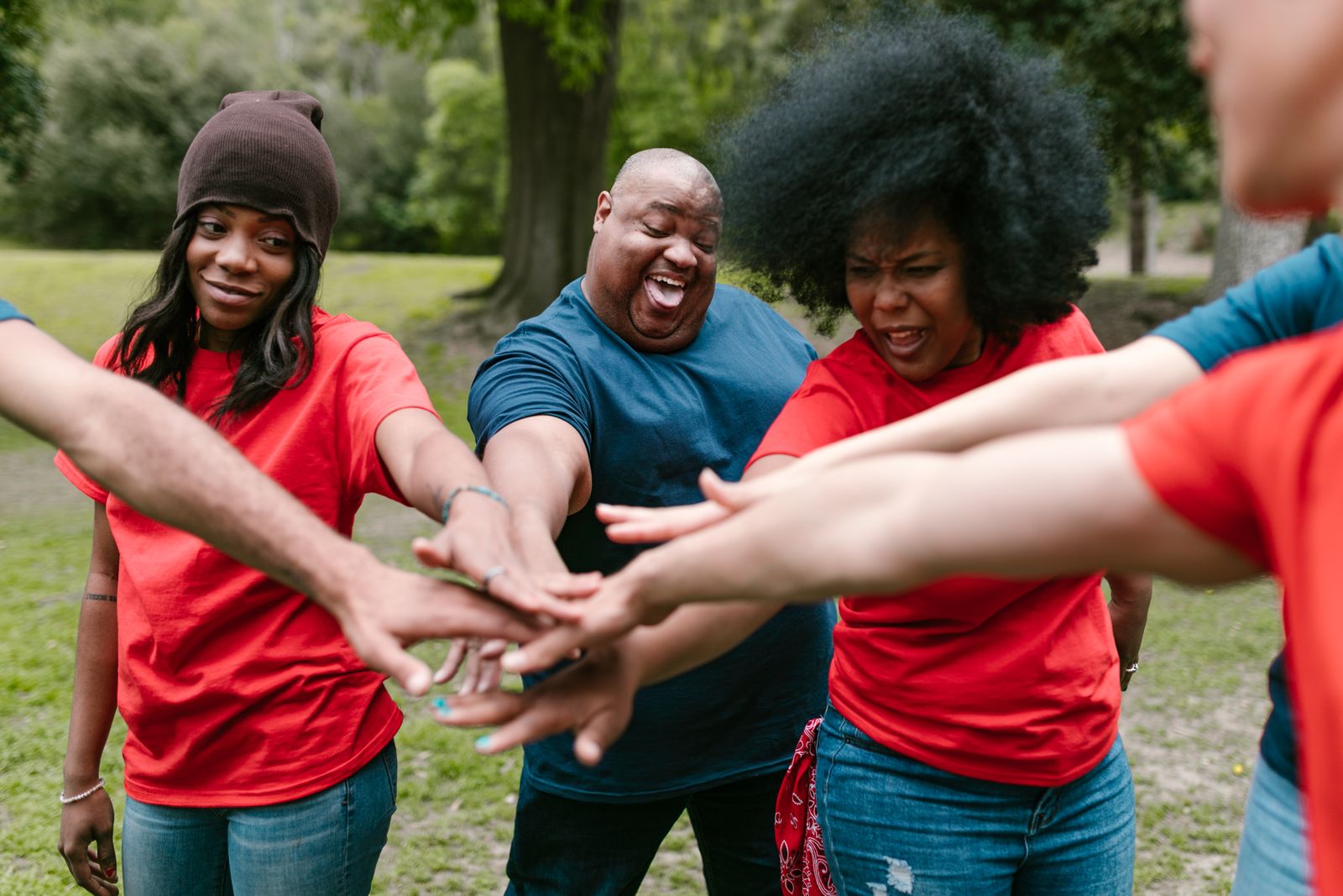 A diverse group joining hands during an outdoor team activity.