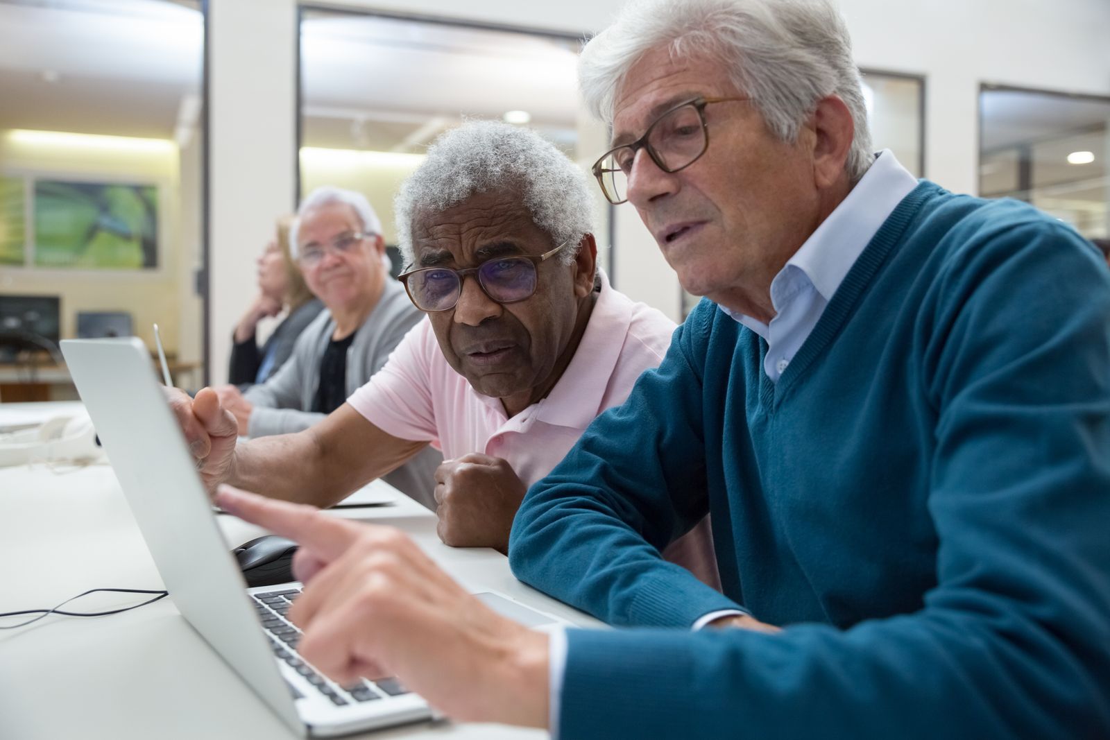 Older adults learning together with a laptop in a classroom.